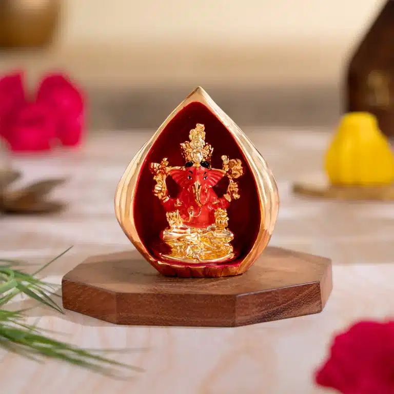 Modak-shaped Ganesha idol with red Ganesha figure on a wooden base